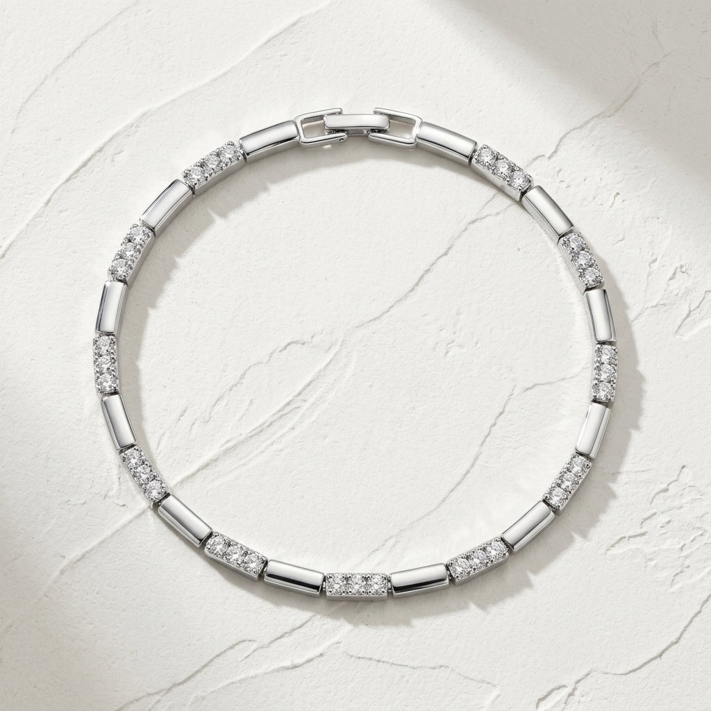 Pulseira de elos lisos com trechos cravejados, banhada a ródio, sobre fundo de gesso claro