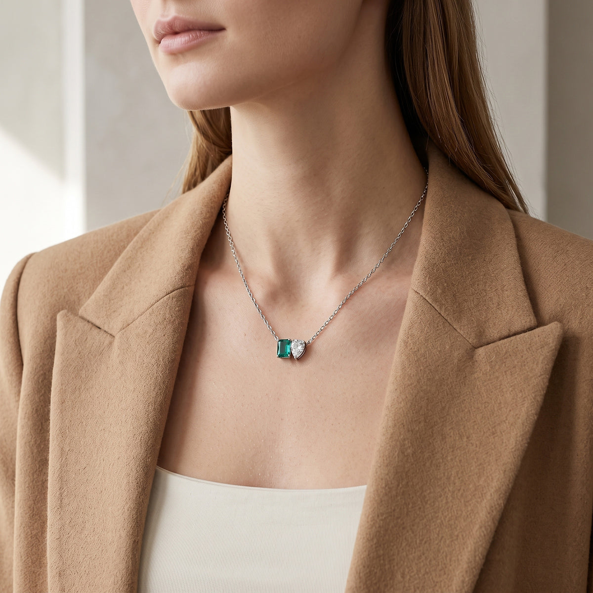 Mulher de blazer caramelo usando a gargantilha de pedra verde e cristal em gota, banhada a ródio