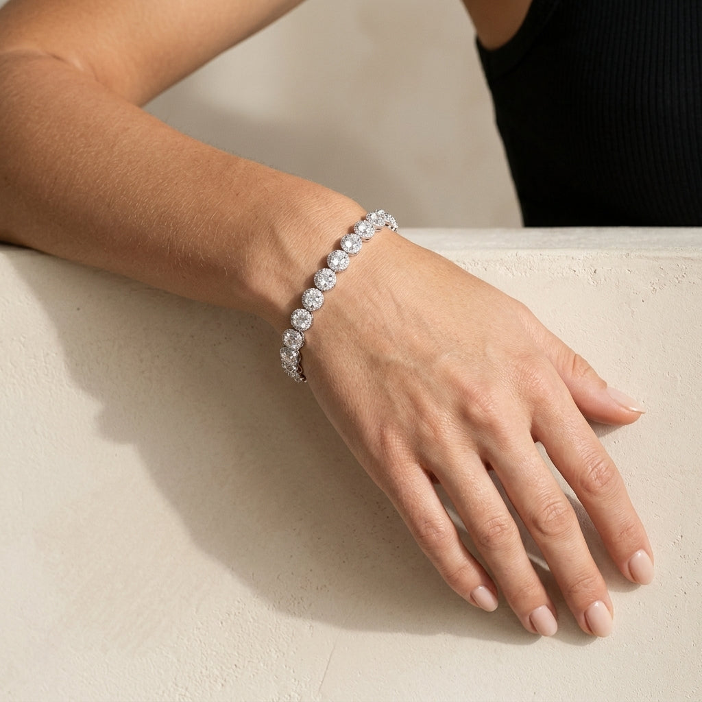 Mão apoiada em superfície clara com a pulseira de zircônias com halo, banhada a ródio
