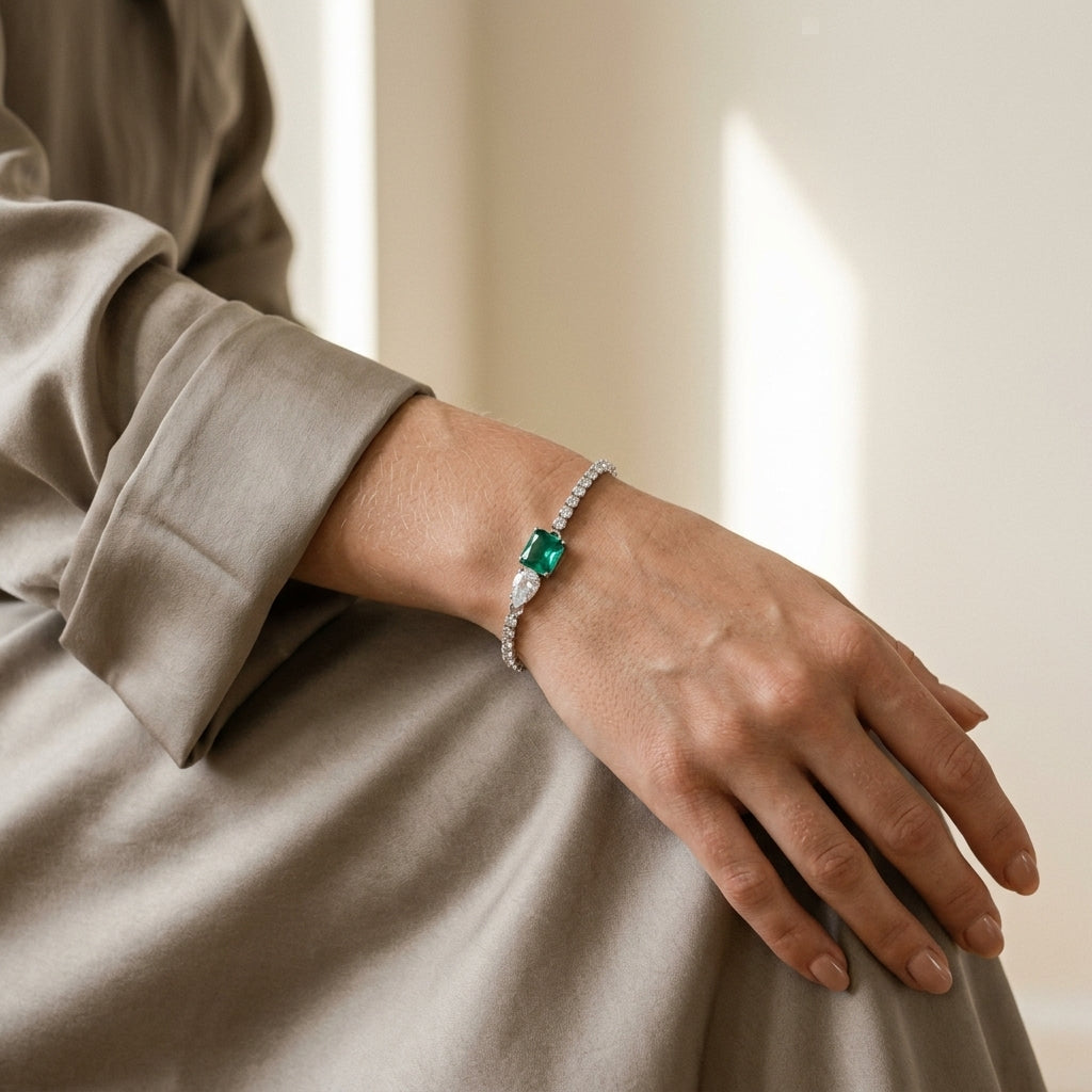 Mulher de blusa bege usando a pulseira riviera de pedra verde, banhada a ródio