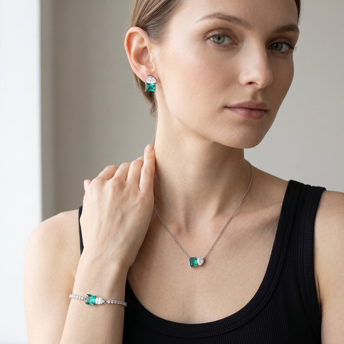 Mulher de regata preta usando a gargantilha e a pulseira de pedra verde, banhadas a ródio