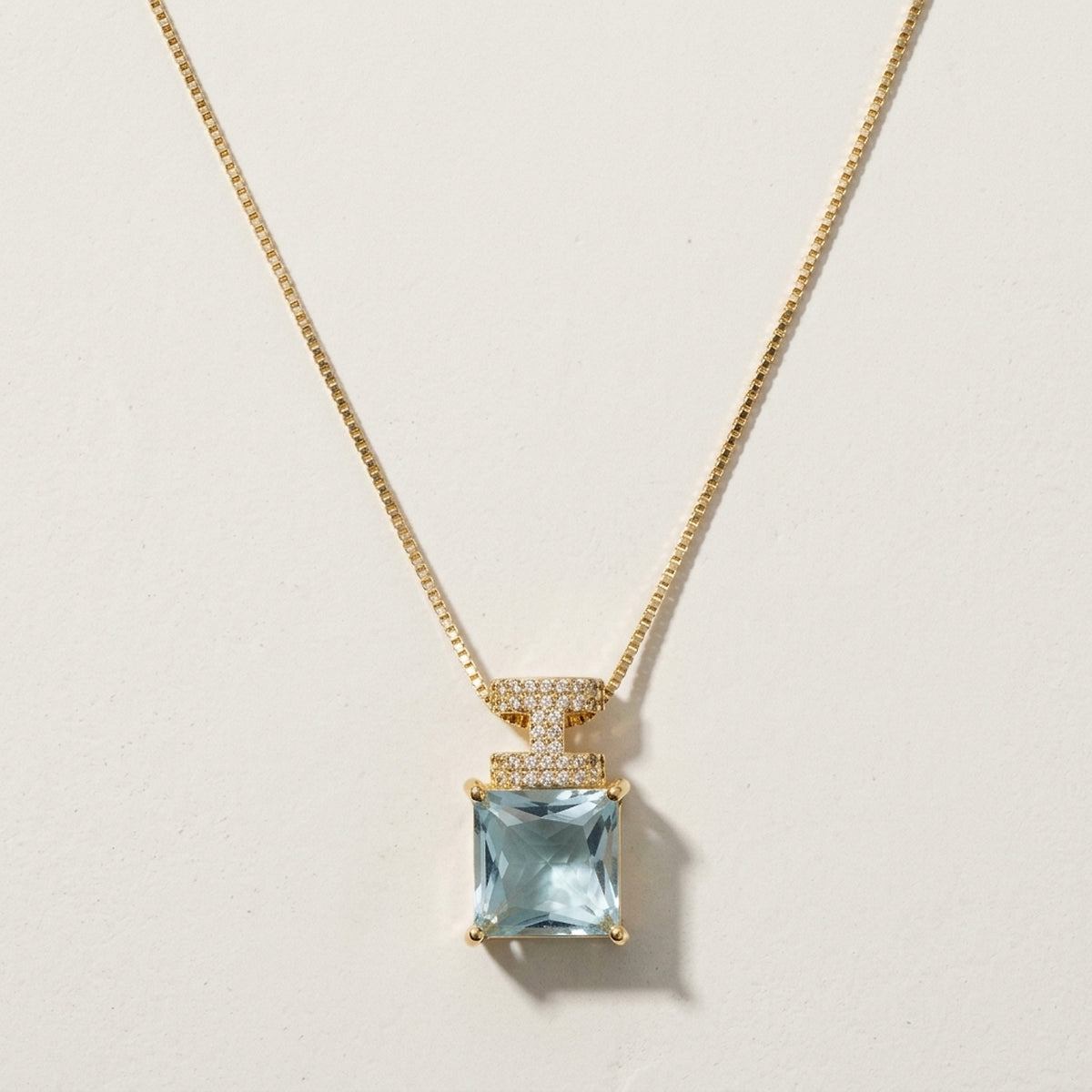 Gargantilha com pingente de pedra azul clara cravejado de zircônias, banhada a ouro