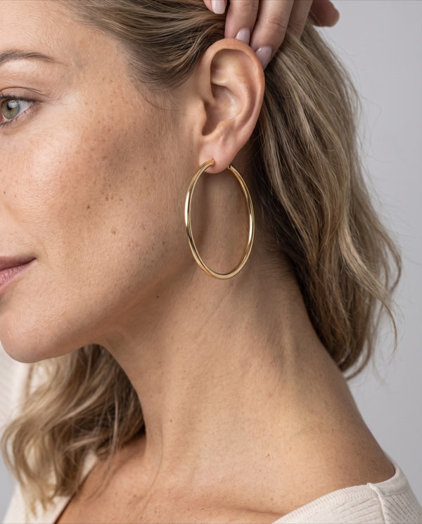 Perfil de mulher prendendo o cabelo atrás da orelha, argola banhada a ouro