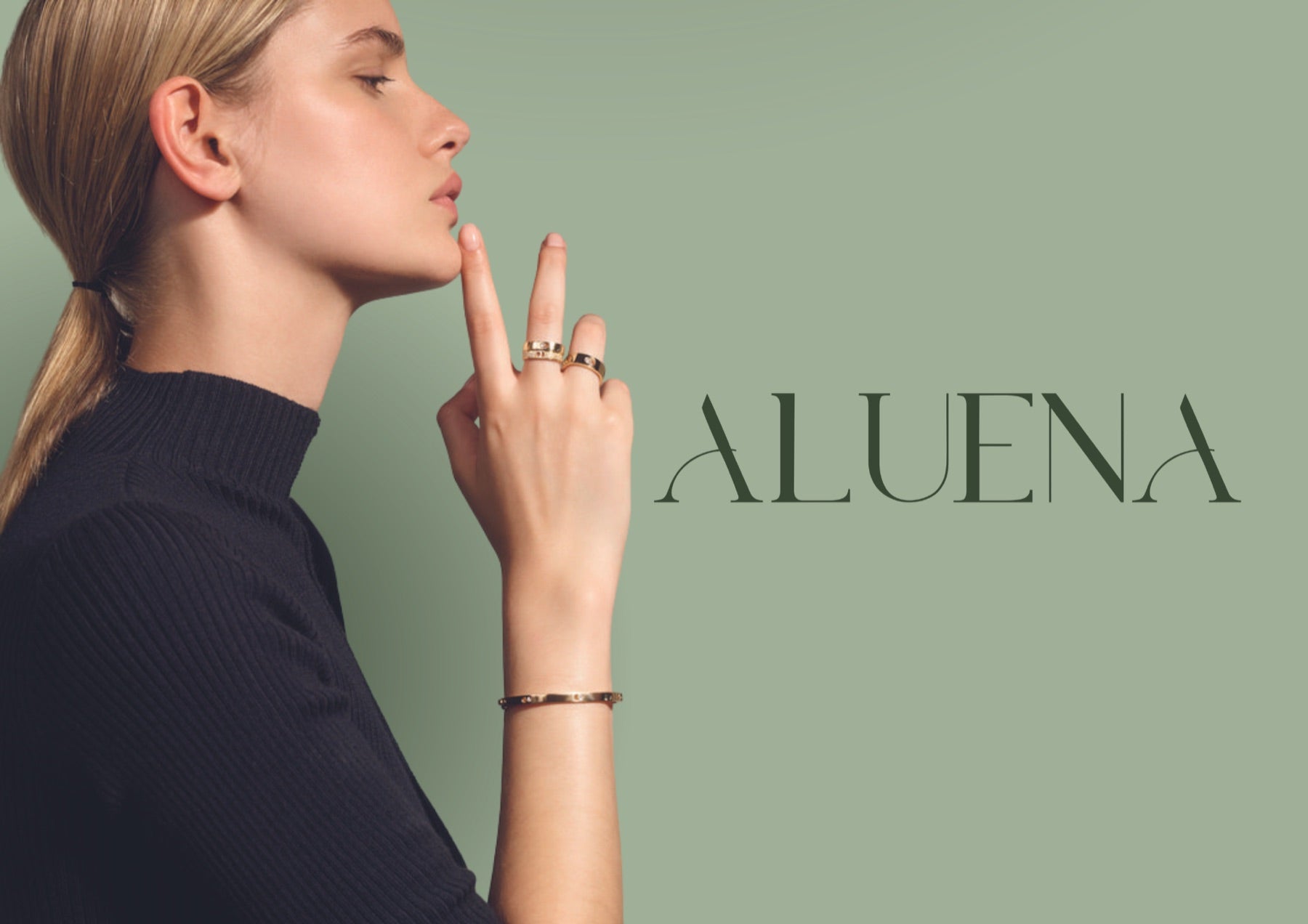 Modelo usando anéis e bracelete banhados a ouro ALUENA sobre fundo verde sálvia